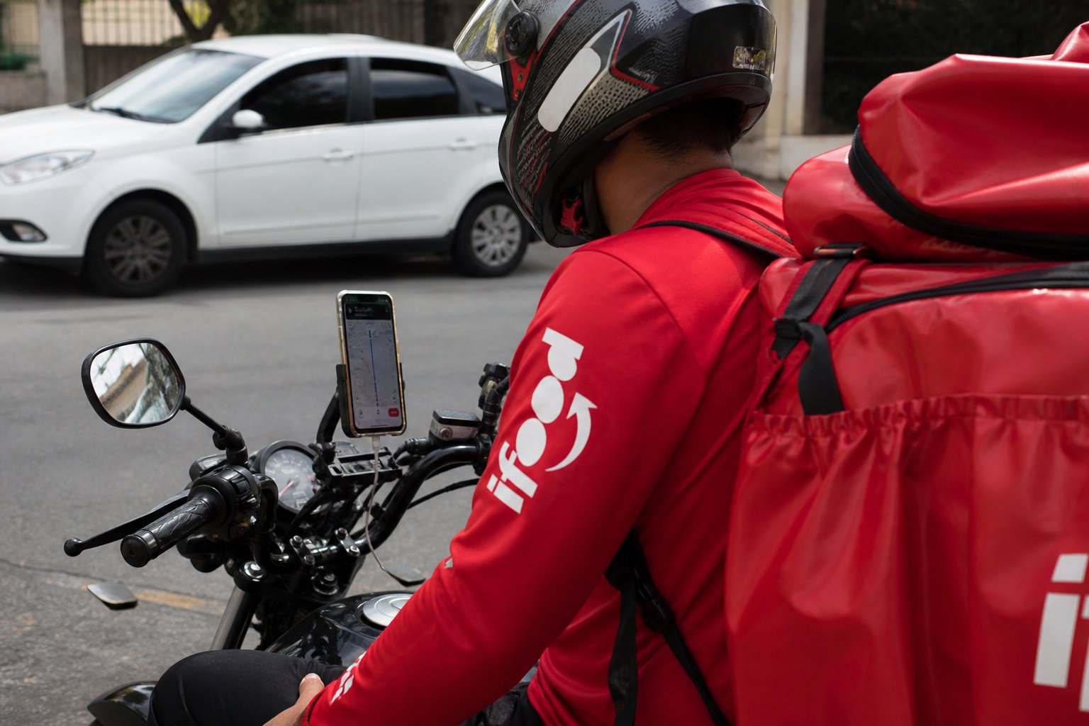 Entregador iFood com celular acoplado na moto — bloqueio de conta em apps